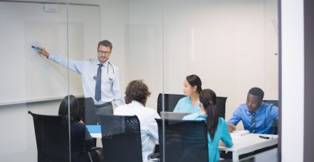 Doctor giving presentation to team of interim doctors at conference room